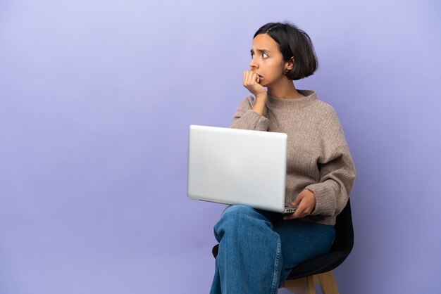 A person looking thoughtfully at a laptop screen in a cozy home office setting.