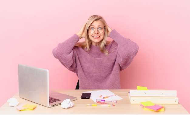 A person sitting at a desk with a laptop, looking a bit overwhelmed.